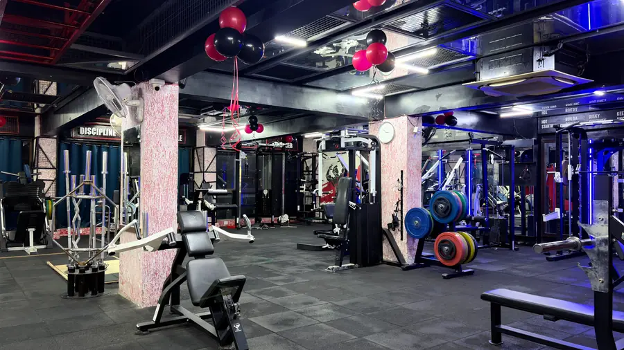 The strength floor seen end to end, lit by the violet ceiling strips